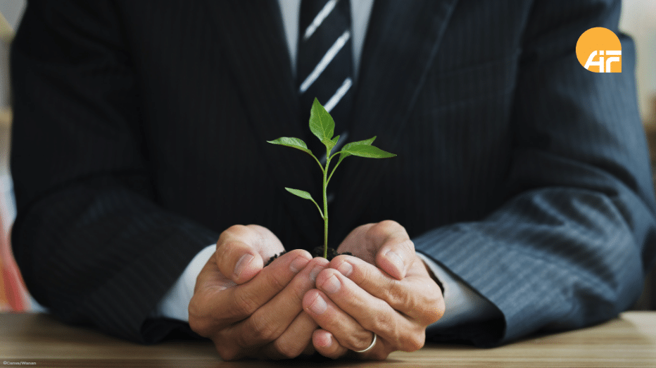 Ein Mann, der eine kleine Pflanze in der Hand hält.