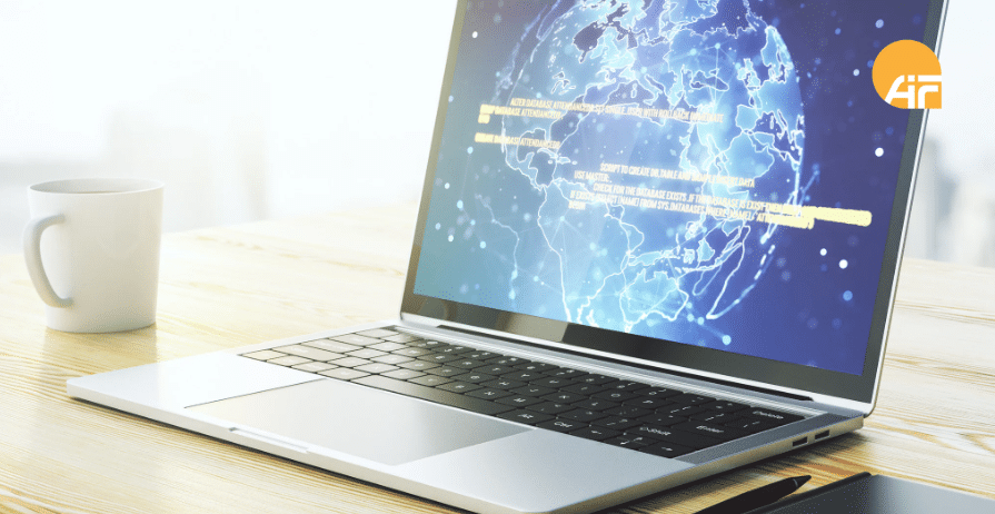 Ein offener Laptop auf einem Arbeitstisch mit einer Tasse daneben.