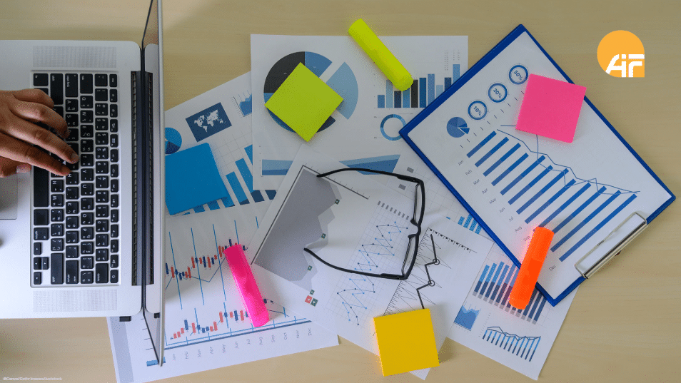 ©Canva/Getty Images/juststock Ein Tisch ist von oben fotografiert. Auf diesem liegen Stifte, Post-its, Diagramme und ein Laptop.