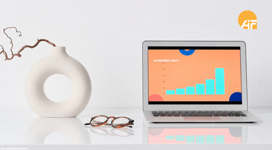Ein Tisch mit einem offenen Laptop, einer Brille und einer Vase.
