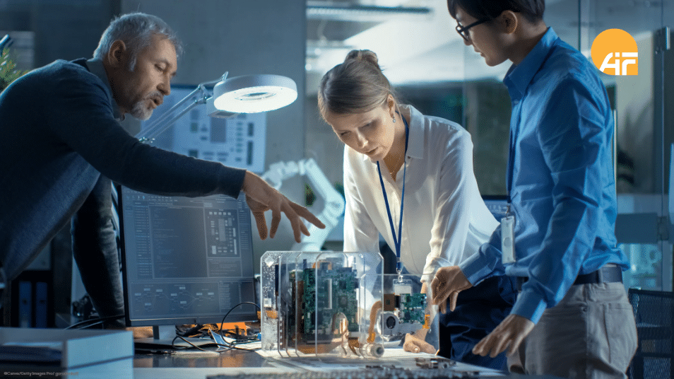 Drei Personen, die über ein technisches Modell gebeugt sind und sich besprechen.